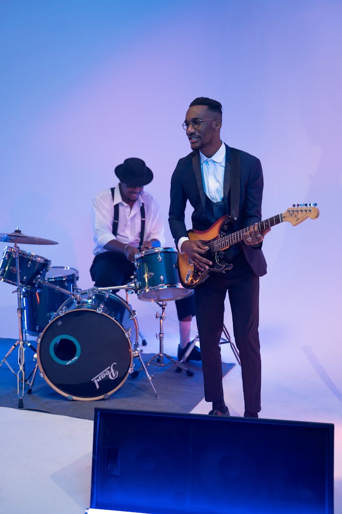 About A band performance featuring a guitarist and drummer in a stylish setting.